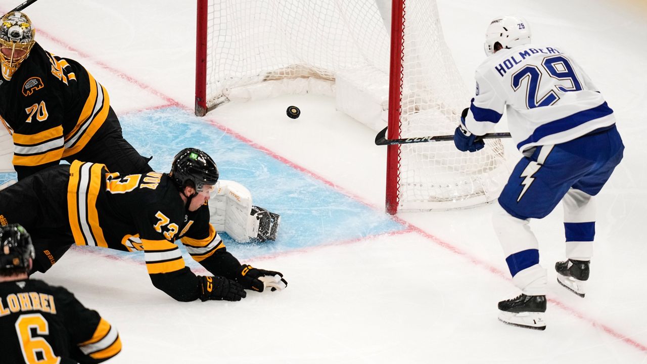 Tampa Bay Lightning right wing Pontus Holmberg (29) pokes the puck into the net, as Boston Bruins goaltender Joonas Korpisalo (70) looks back at the crease, during the second period of an NHL hockey game, Monday, Oct. 13, 2025, in Boston. (AP Photo/Charles Krupa)