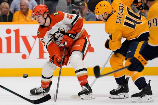 Ducks right wing Beckett Sennecke, left, passes the puck away...