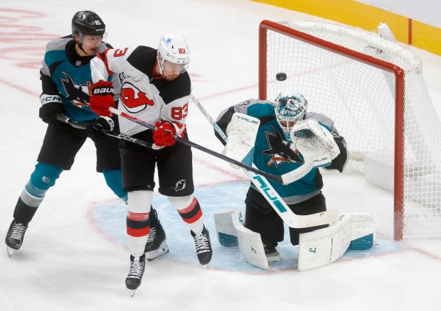 The puck flies over San Jose Sharks goaltender Alex Nedeljkovic...
