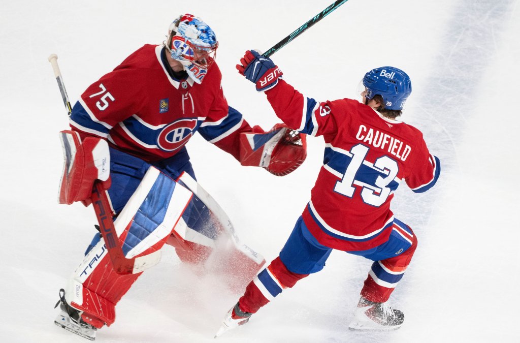 Two Montreal Canadiens hockey players, a goalie and a forward named Caufield, on the ice during a game.