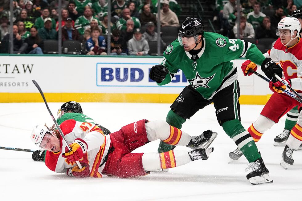 Calgary Flames' Connor Zary (47) falls to the ice after being stripped of the puck by Dallas...