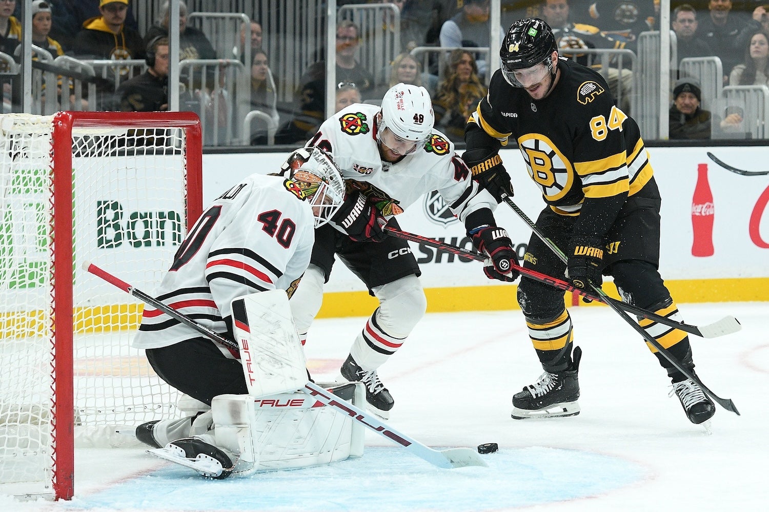 Oct 9, 2025; Boston, Massachusetts, USA; Chicago Blackhawks goaltender Arvid Soderblom (40) makes a save in front of Boston Bruins left wing Tanner Jeannot (84) and defenseman Matt Grzelcyk (48) during the third period at TD Garden. Mandatory Credit: Bob DeChiara-Imagn Images