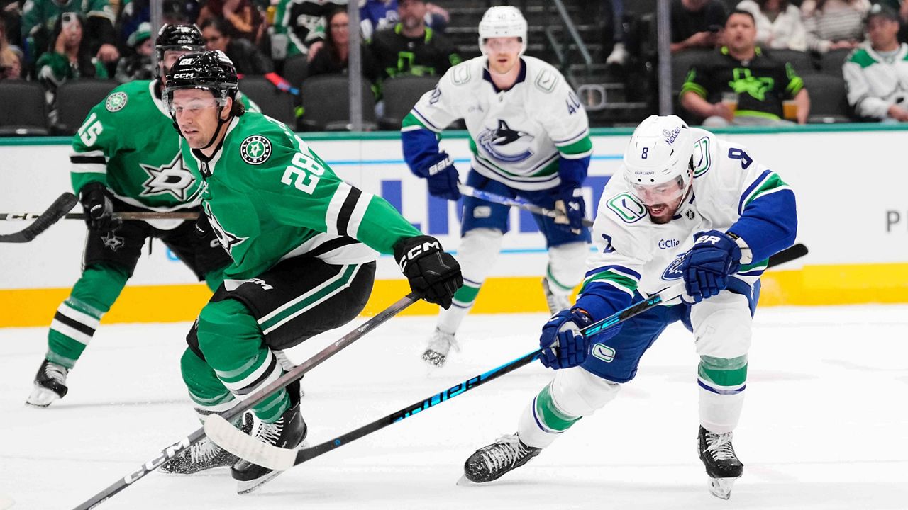 Vancouver Canucks right wing Conor Garland (8) shoots and scores on a shot behind Dallas Stars defenseman Alexander Petrovic (28) in the second period of an NHL hockey game Thursday, Oct. 16, 2025, in Dallas. (AP Photo/Tony Gutierrez)