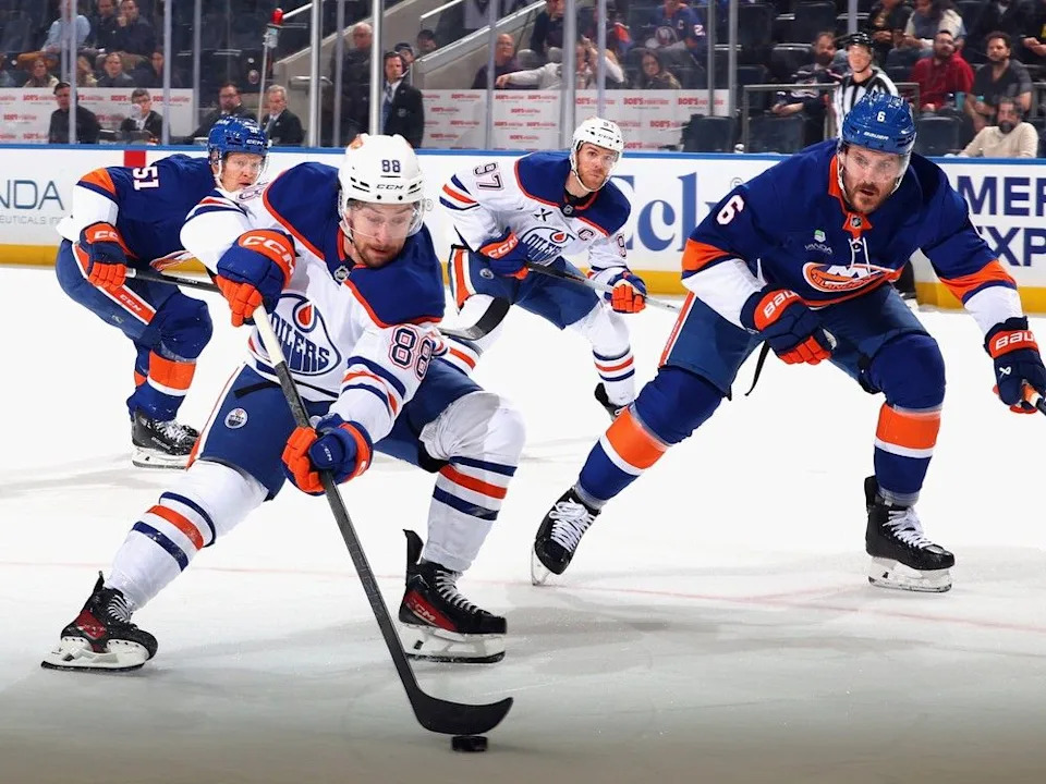 Andrew Mangiapane #88 of the Edmonton Oilers attempts to get past Ryan Pulock #6 of the New York Islanders during the first period at UBS Arena on October 16, 2025 in Elmont, New York.