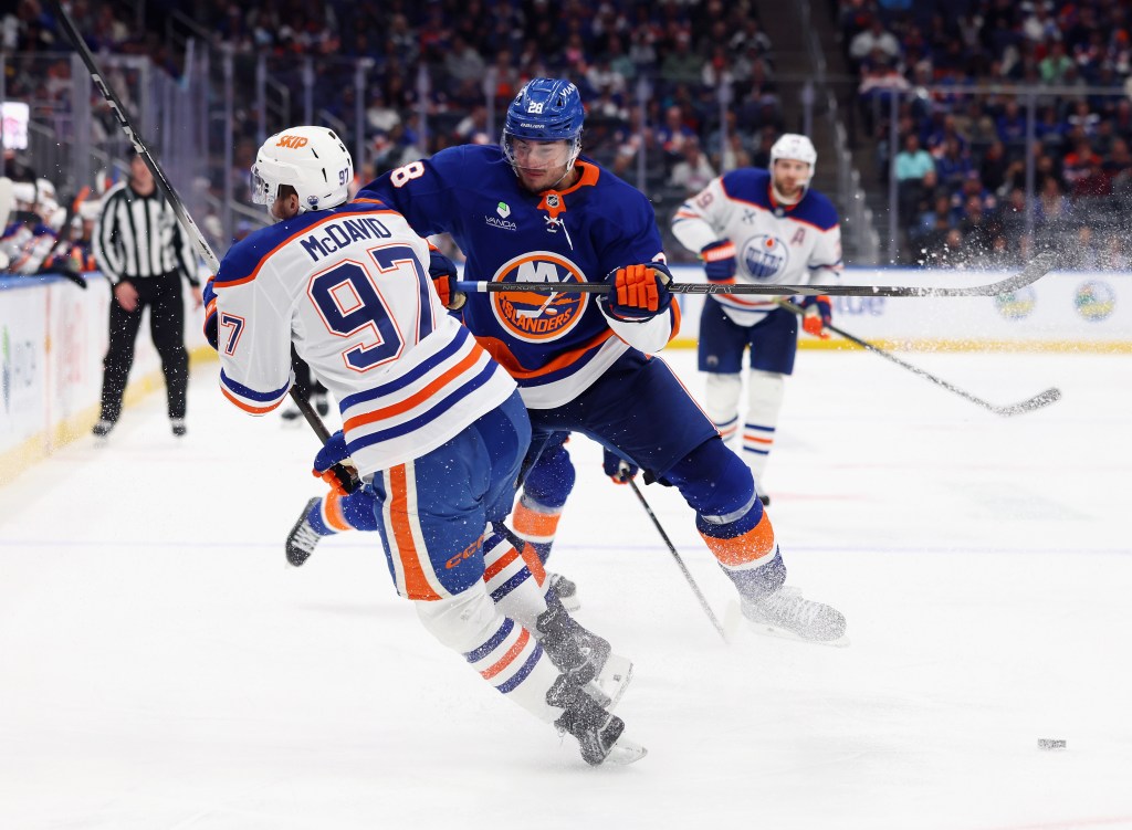Alexander Romanov #28 of the New York Islanders checks Connor McDavid #97 of the Edmonton Oilers during the third period at UBS Arena on October 16, 2025 in Elmont, New York.