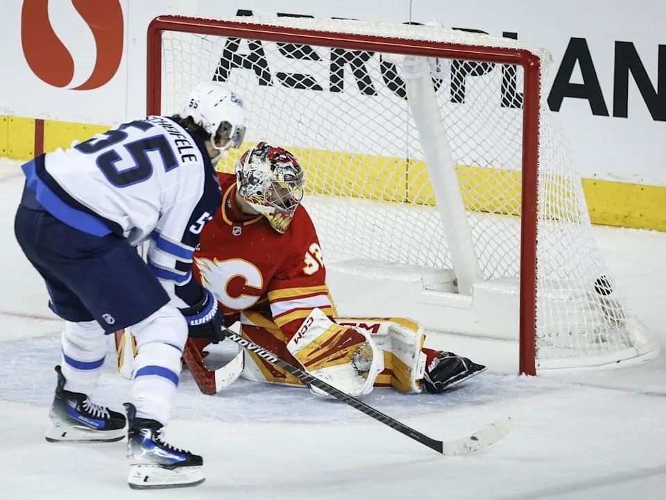 Winnipeg Jets’ Mark Scheifele, left, scores on Calgary Flames goalie Dustin Wolf during third period NHL hockey action in Calgary, Alta., Monday, Oct. 20, 2025.