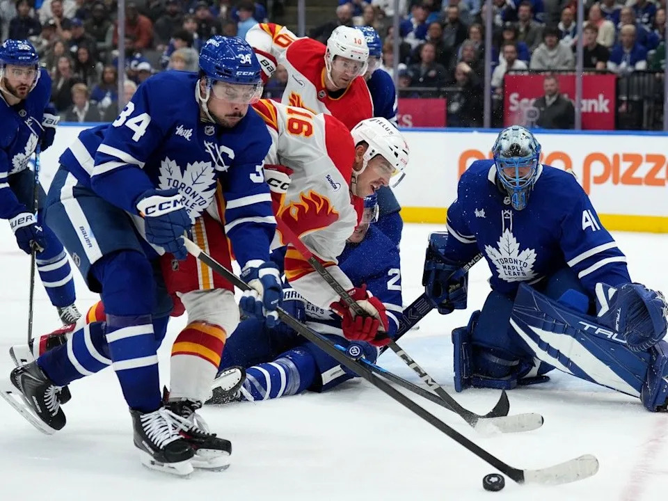  Maple Leafs forward Auston Matthews and Flames forward Morgan Frost battle for the puck on Tuesday.