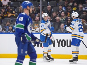 St. Louis Blues' Jimmy Snuggerud (21) and Pius Suter (22) celebrate Snuggerud's goal as Elias Pettersson skates past during the first period