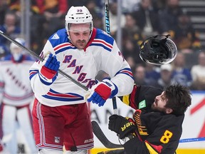 Conor Garland (8) loses his helmet as he's checked by Sam Carrick during the first period