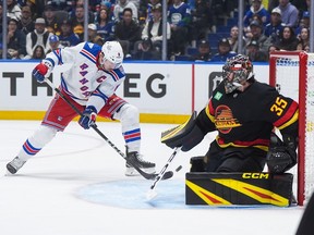 J.T. Miller, back left, misses the net behind Vancouver Canucks goalie Thatcher Demko during the first period