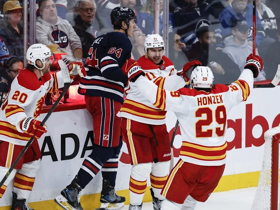 The Flames’ Blake Coleman (20), Mikael Backlund and Samuel Honzek celebrate Backlund’s goal on Friday.
