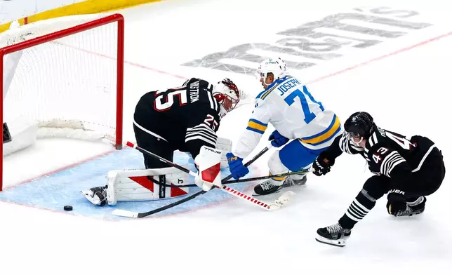 New Jersey Devils goaltender Jacob Markstrom and defenseman Luke Hughes defend against St. Louis Blues right wing Mathieu Joseph during the third period of an NHL hockey game, Wednesday, Nov. 26, 2025, in Newark, N.J. (AP Photo/Noah K. Murray)