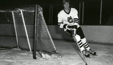 A black and white photo of David Sherlock on the ice, skating around the goal