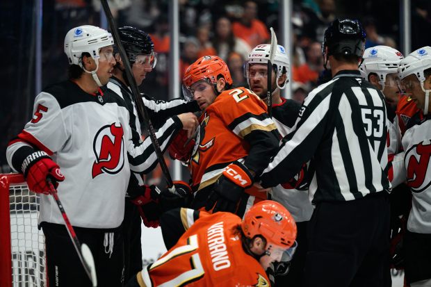 Ducks center Jansen Harkins, center, is held back after colliding...