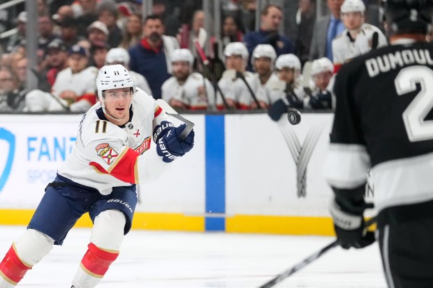 Florida Panthers right wing Mackie Samoskevich, left, passes the puck...