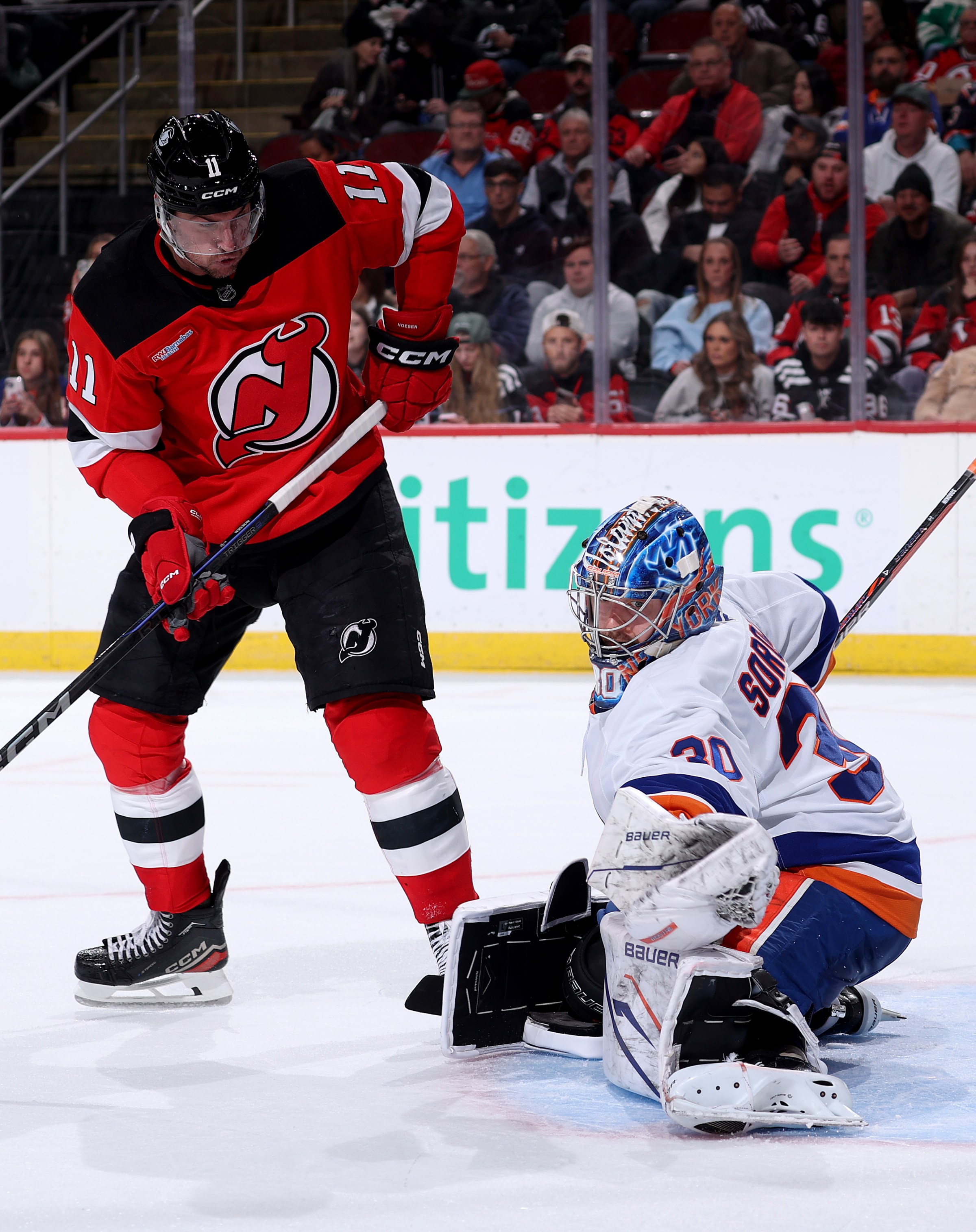 NEWARK, NEW JERSEY - NOVEMBER 10: Ilya Sorokin #30 of the New York Islanders stops a shot as Stefan Noesen #11 of the New Jersey Devils looks on during the second period at Prudential Center on November 10, 2025 in Newark, New Jersey. (Photo by Elsa/Getty Images)