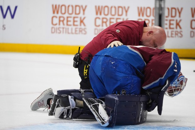 Colorado Avalanche goaltender Scott Wedgewood, front, is attended to by...
