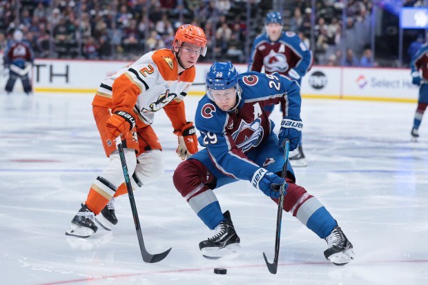 Colorado Avalanche star Nathan MacKinnon, right, skates with the puck...