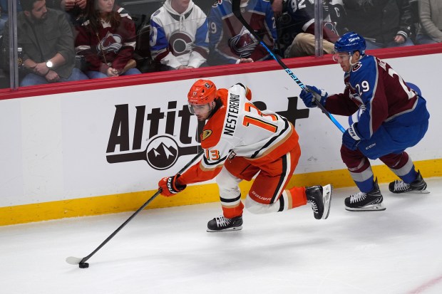 Ducks center Nikita Nesterenko, left, collects the puck as Colorado...