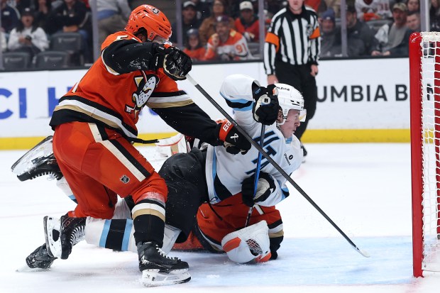 Ducks goaltender Lukas Dostal, bottom, and teammate Olen Zellweger, left,...