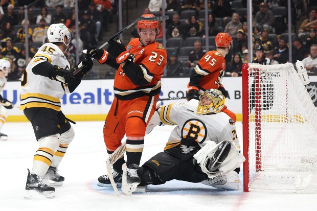 The Ducks’ Mason McTavish (23) collides with Boston Bruins goaltender...