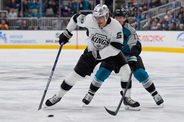 Kings right wing Quinton Byfield, left, moves the puck while...