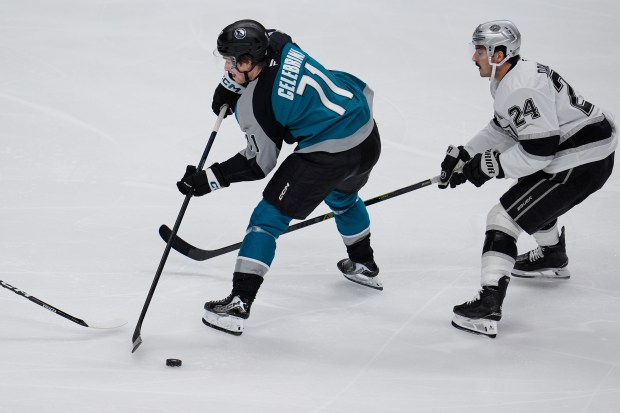 San Jose Sharks center Macklin Celebrini, left, passes the puck...