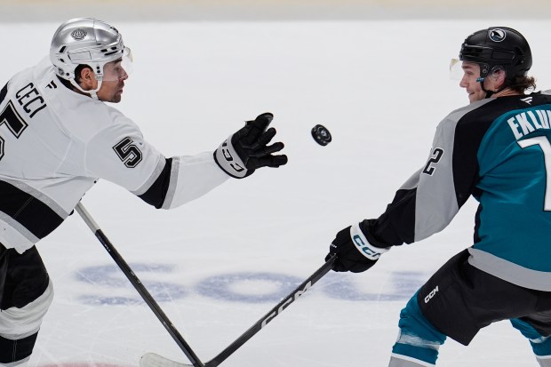 Kings defenseman Cody Ceci, left, knocks the puck out of...