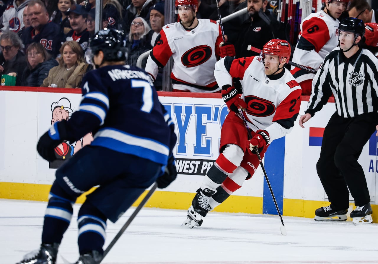A player in white and red skates along the boards.