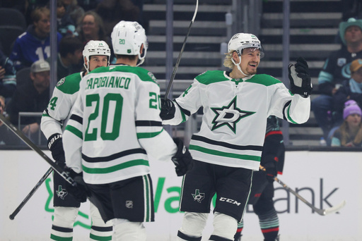 Dallas Stars center Roope Hintz, right, celebrates with defenseman Kyle Capobianco (20) and left wing Jamie Benn (14) after scoring during the first period of an NHL hockey game against the Seattle Kraken Wednesday, Nov. 26, 2025, in Seattle. (AP Photo/Jason Redmond)