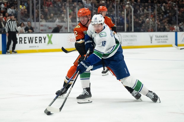 Ducks defenseman Jackson Lacombe, left, blocks a shot by Vancouver...