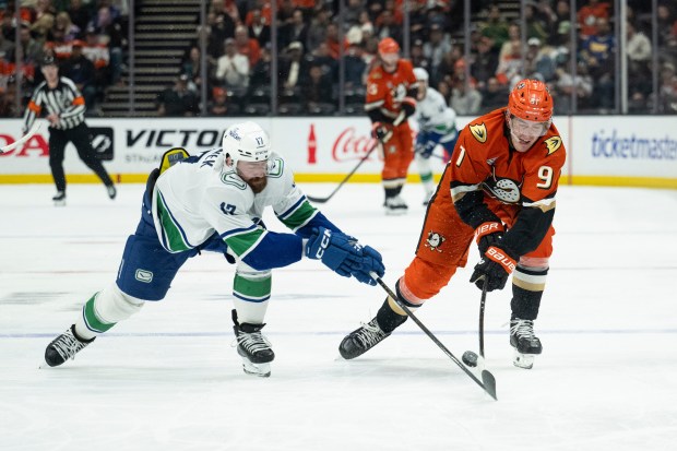 Ducks center Leo Carlsson, right, vies for the puck against...