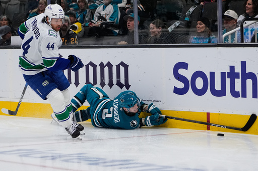 San Jose Sharks defenseman John Klingberg (3) falls on the ice as Vancouver Canucks left wing Kiefer Sherwood (44) chases after the puck during the second period of an NHL hockey game, Friday, Nov. 28, 2025, in San Jose, Calif. (AP Photo/Godofredo A. V&aacute;squez)