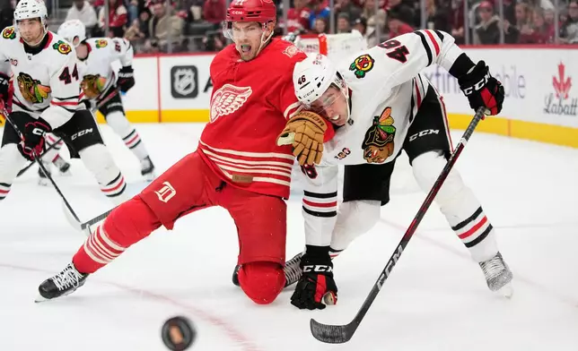 Detroit Red Wings left wing James van Riemsdyk, left, and Chicago Blackhawks defenseman Louis Crevier, right, vie for the puck during the second period of an NHL hockey game Sunday, Nov. 9, 2025, in Detroit. (AP Photo/Ryan Sun)