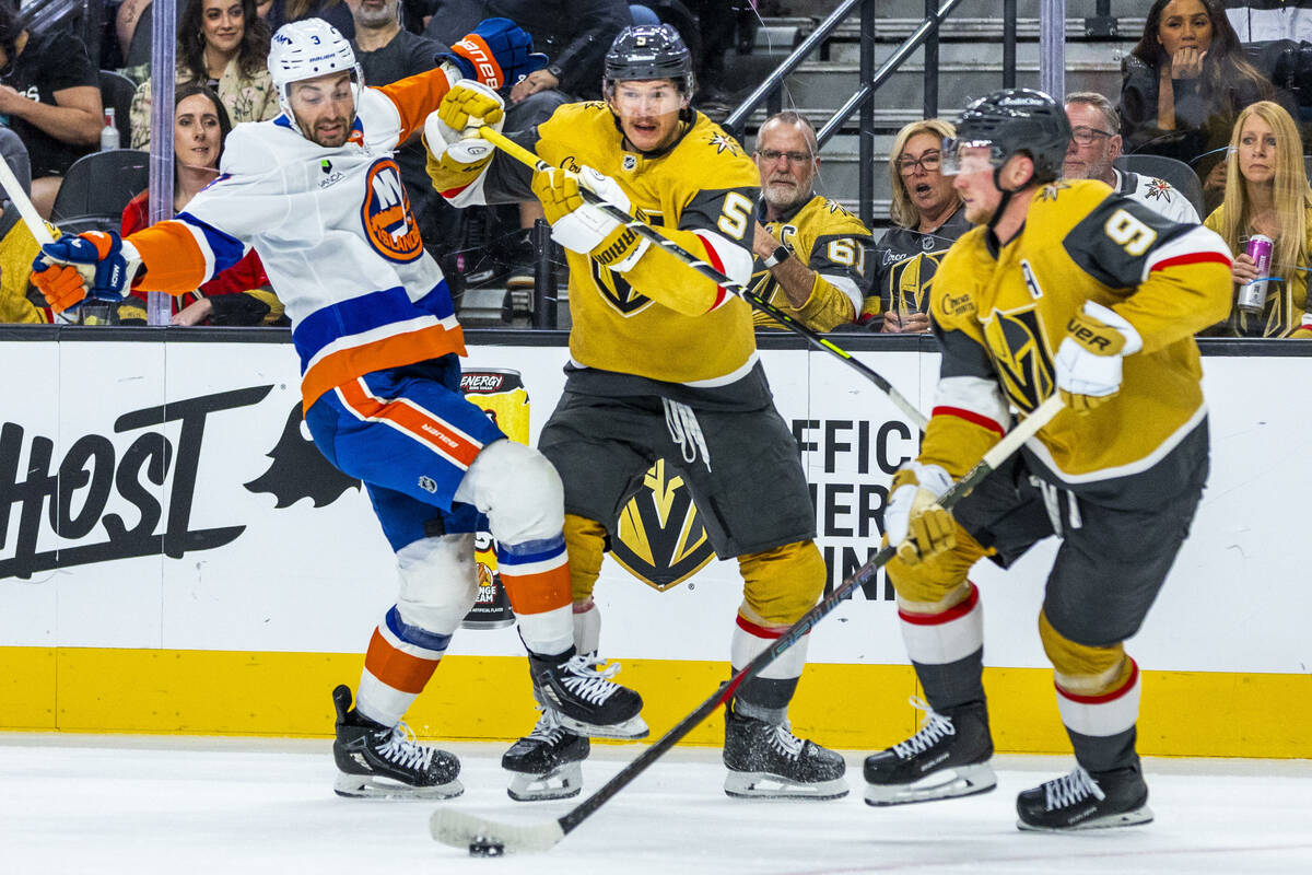 Golden Knights defenseman Jeremy Lauzon (5) checks New York Islanders defenseman Adam Pelech (3 ...