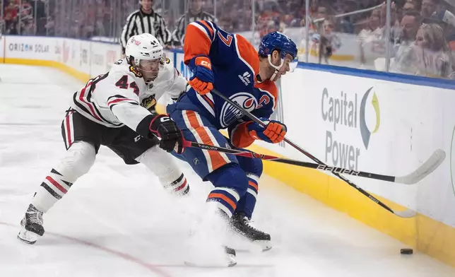 Chicago Blackhawks' Wyatt Kaiser (44) and Edmonton Oilers' Connor McDavid (97) battle for the puck during second period NHL action, in Edmonton on Saturday, Nov. 1, 2025. (Jason Franson/The Canadian Press via AP)