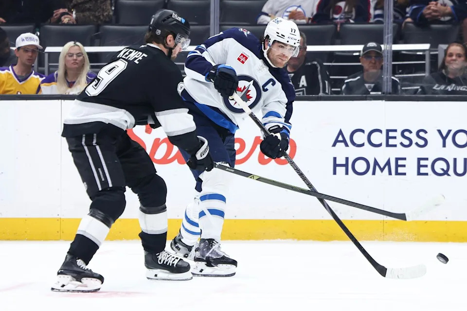 Winnipeg Jets center Adam Lowry, right, passes the puck against Los Angeles Kings right wing Adrian Kempe (9) during the third period of an NHL hockey game, Tuesday, Nov. 4, 2025, in Los Angeles. (AP Photo/Jessie Alcheh)