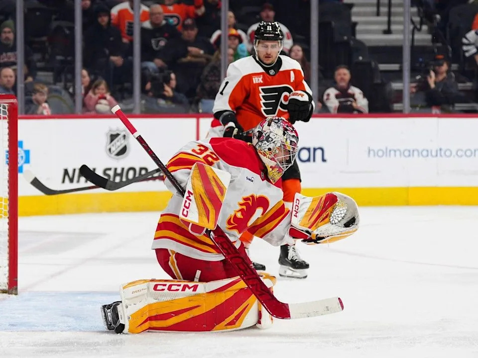 Calgary Flames goaltender Dustin Wolf (32) makes a glove-save during the second period of an NHL hockey game against the Philadelphia Flyers, Sunday, Nov. 2, 2025, in Philadelphia.