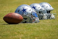 Dallas Cowboys helmets rest on the field during a training camp walk-through on Aug. 4,...