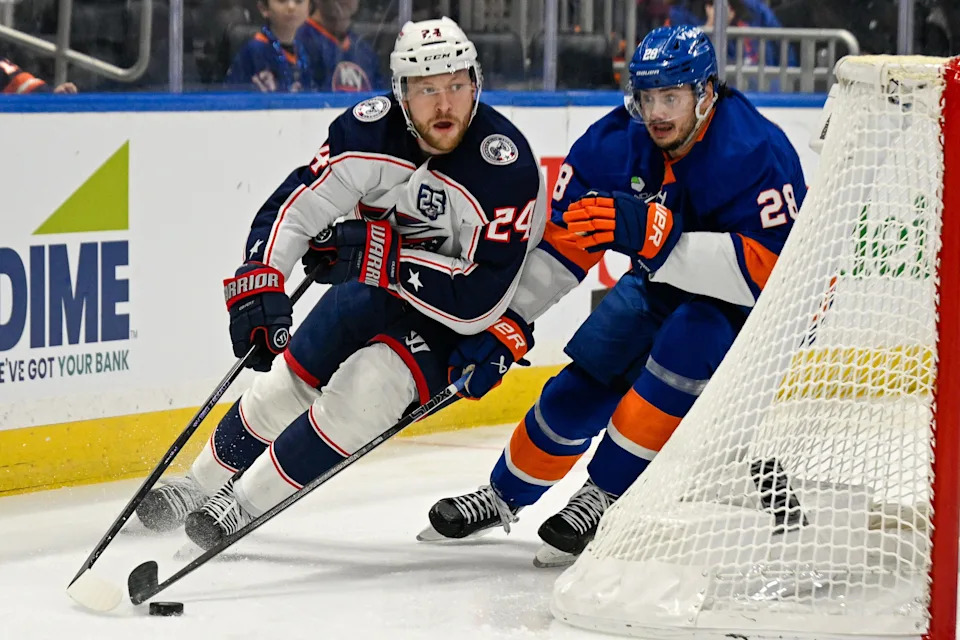 Nov 2, 2025; Elmont, New York, USA; Columbus Blue Jackets right wing Mathieu Olivier (24) skates the puck from behind the net chased by New York Islanders defenseman Alexander Romanov (28) during the first period at UBS Arena. Mandatory Credit: Dennis Schneidler-Imagn Images