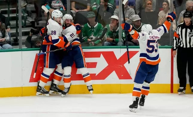 New York Islanders defenseman Alexander Romanov (28) and center Casey Cizikas (53) celebrate a goal by center Kyle Palmieri (21) during the third period of an NHL hockey game against the Dallas Stars, Tuesday, Nov. 18, 2025, in Dallas. (AP Photo/Gareth Patterson)