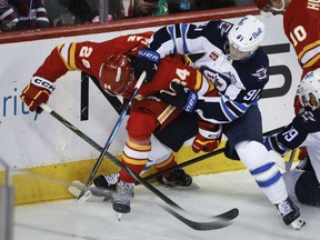 Winnipeg Jets' Cole Perfetti (91) and Calgary Flames' Jake Bean battle for the puck during second period NHL hockey action in Calgary, Alta., Saturday, Nov. 15, 2025.