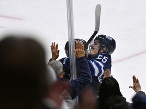 Winnipeg Jets' Logan Stanley (64) celebrates with Mark Scheifele (55) after he scored on the Columbus Blue Jackets during the third period of their NHL hockey game in Winnipeg, Tuesday November 18, 2025.
