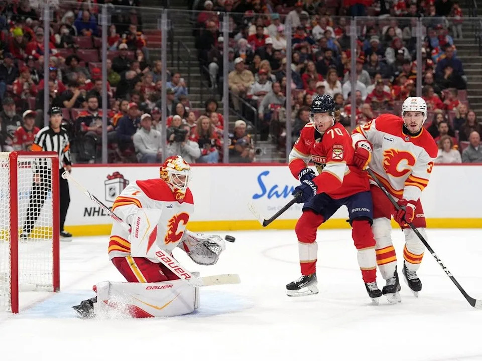  Flames goaltender Devin Cooley stops a shot as Panthers forward Jesper Boqvist and Flames defenceman Yan Kuznetsov battle for position.