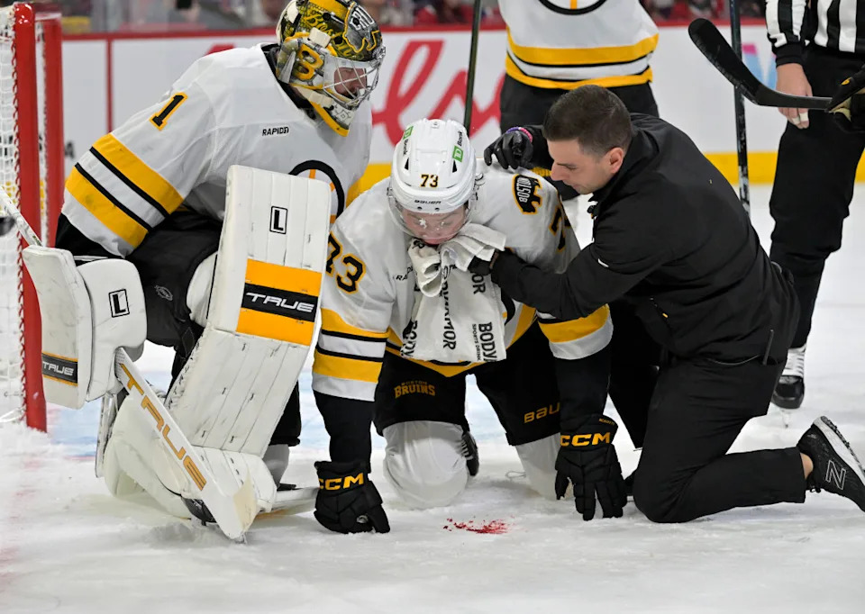 Boston Bruins defenseman Charlie McAvoy (73) is tended by a trainer after receiving a shot in the mouth.Eric Bolte-Imagn Images