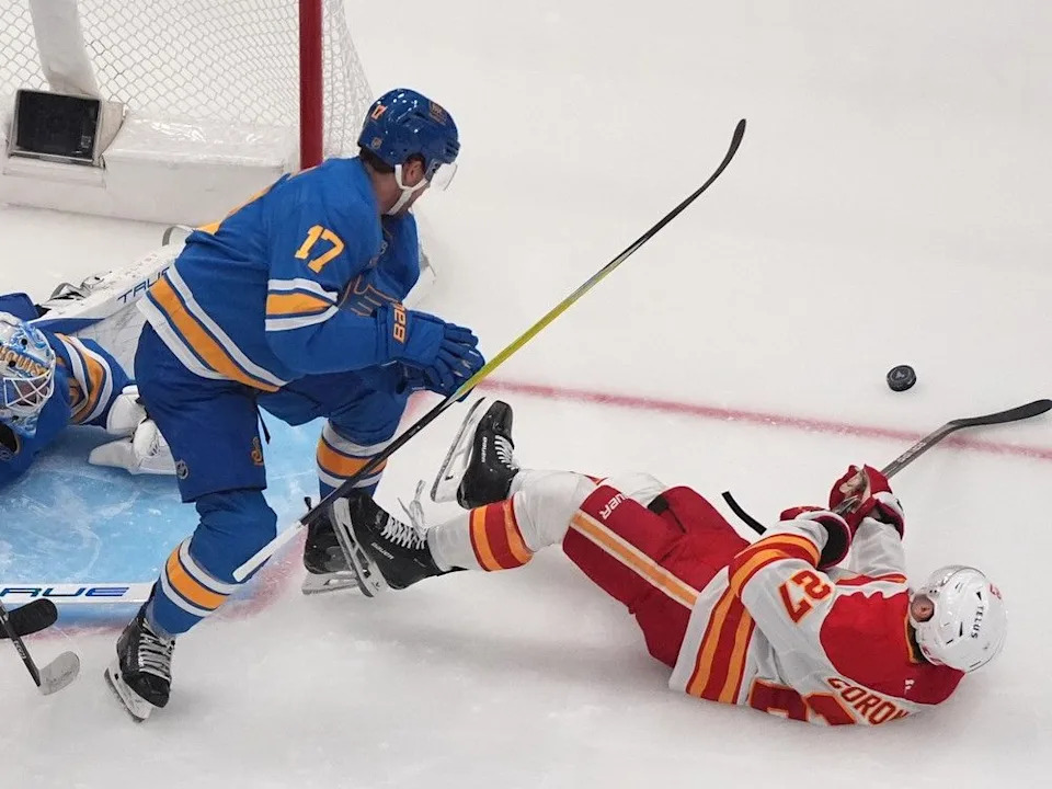  Calgary Flames’ Matt Coronato (27) and St. Louis Blues’ Cam Fowler (17) battle for a loose puck during the second period of an NHL hockey game Tuesday, Nov. 11, 2025, in St. Louis.
