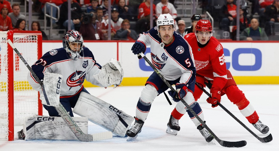 Nov 22, 2025; Detroit, Michigan, USA; Columbus Blue Jackets defenseman Denton Mateychuk (5) and Detroit Red Wings center Emmitt Finnie (58) fight for position in front of goaltender Jet Greaves (73) in the second period at Little Caesars Arena.