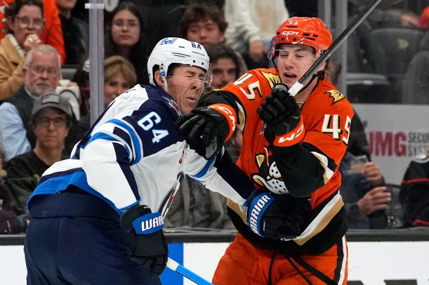 Winnipeg Jets defenseman Logan Stanley, left, is hit in the...