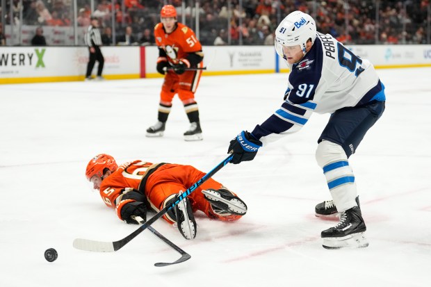 Winnipeg Jets center Cole Perfetti, right,, takes a shot as...