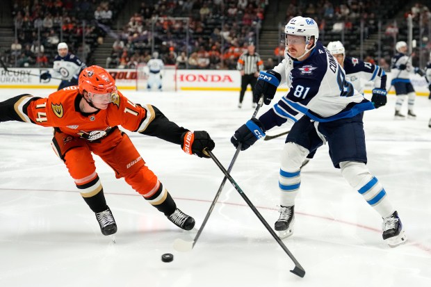 Winnipeg Jets left wing Kyle Connor, right, passes the puck...
